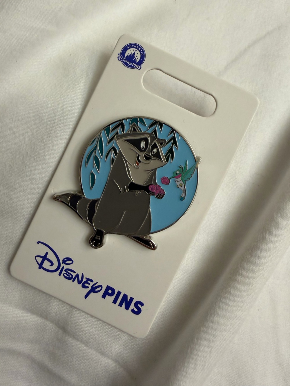 Disney Gray Meeko Raccoon Enamel Pin with Blue Backdrop and Pink Flower